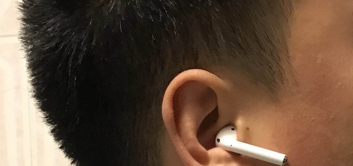 A close up of an ear with a single white Apple AirPod